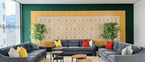 A modern living room with two grey sofas, a wooden coffee table, and a patterned wall divider.