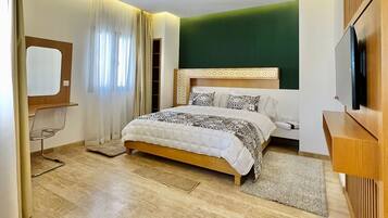 Un dormitorio moderno con una cama grande, televisión y escritorio.