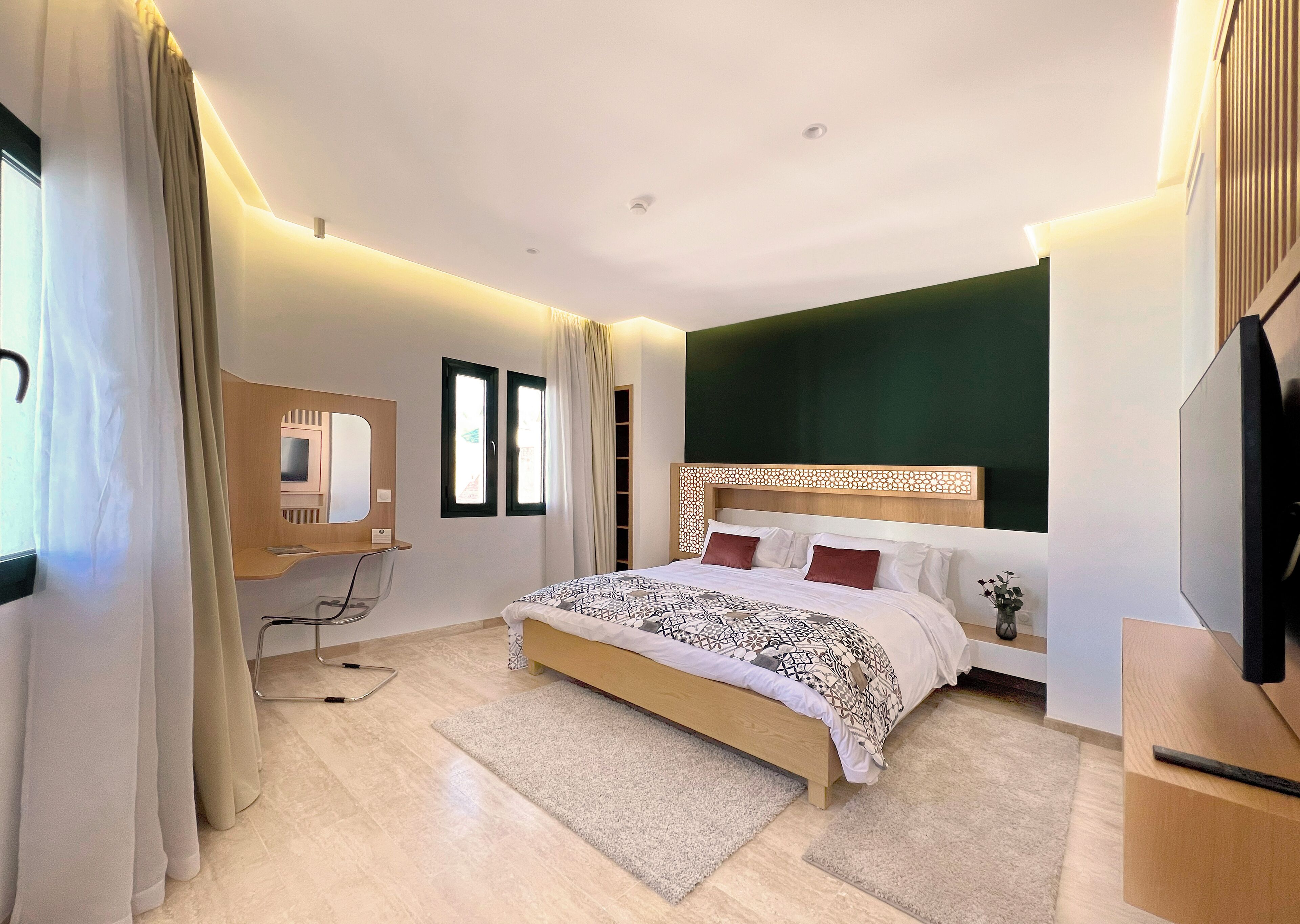 Un dormitorio moderno con una cama grande, un escritorio y una televisión.