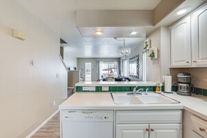 A kitchen with white cabinets, a dishwasher, a sink, and a coffee maker.
