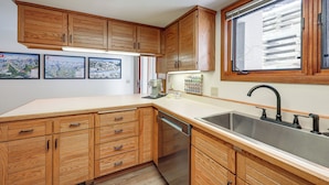 A kitchen with wooden cabinets, a stainless steel sink, and a dishwasher. - Walk to Chairlifts: Breck Condo w/ Private Patio (Breckenridge)