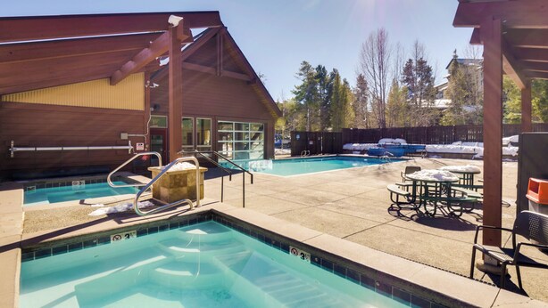 A pool area with a wooden deck, lounge chairs, and a covered seating area. - Walk to Chairlifts: Breck Condo w/ Private Patio (Breckenridge)