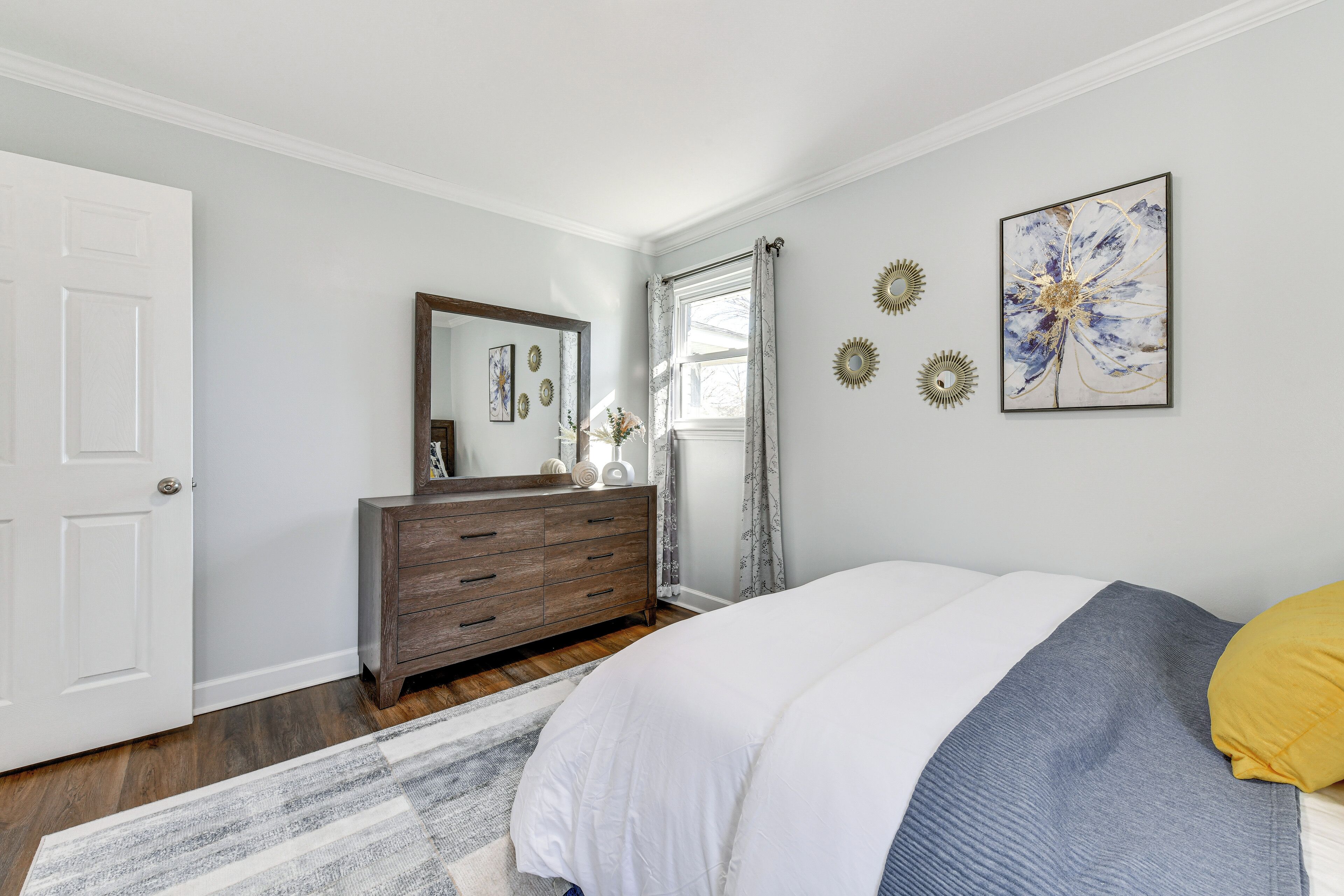 Un dormitorio con cama, cómoda, espejo y decoración mural.