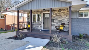 A modern house with a covered porch, stone exterior, and a door with a window.