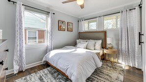 A bedroom with a bed, a ceiling fan, a nightstand, and a window with curtains.
