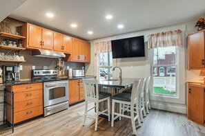 A modern kitchen with wooden cabinets, stainless steel appliances, and a central island with bar stools.