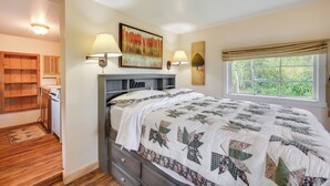 A bedroom with a bed, a window with a view, a lamp, and a shelf. - 'minnehaha' Allenspark Cabin Near Hiking! (Allenspark)