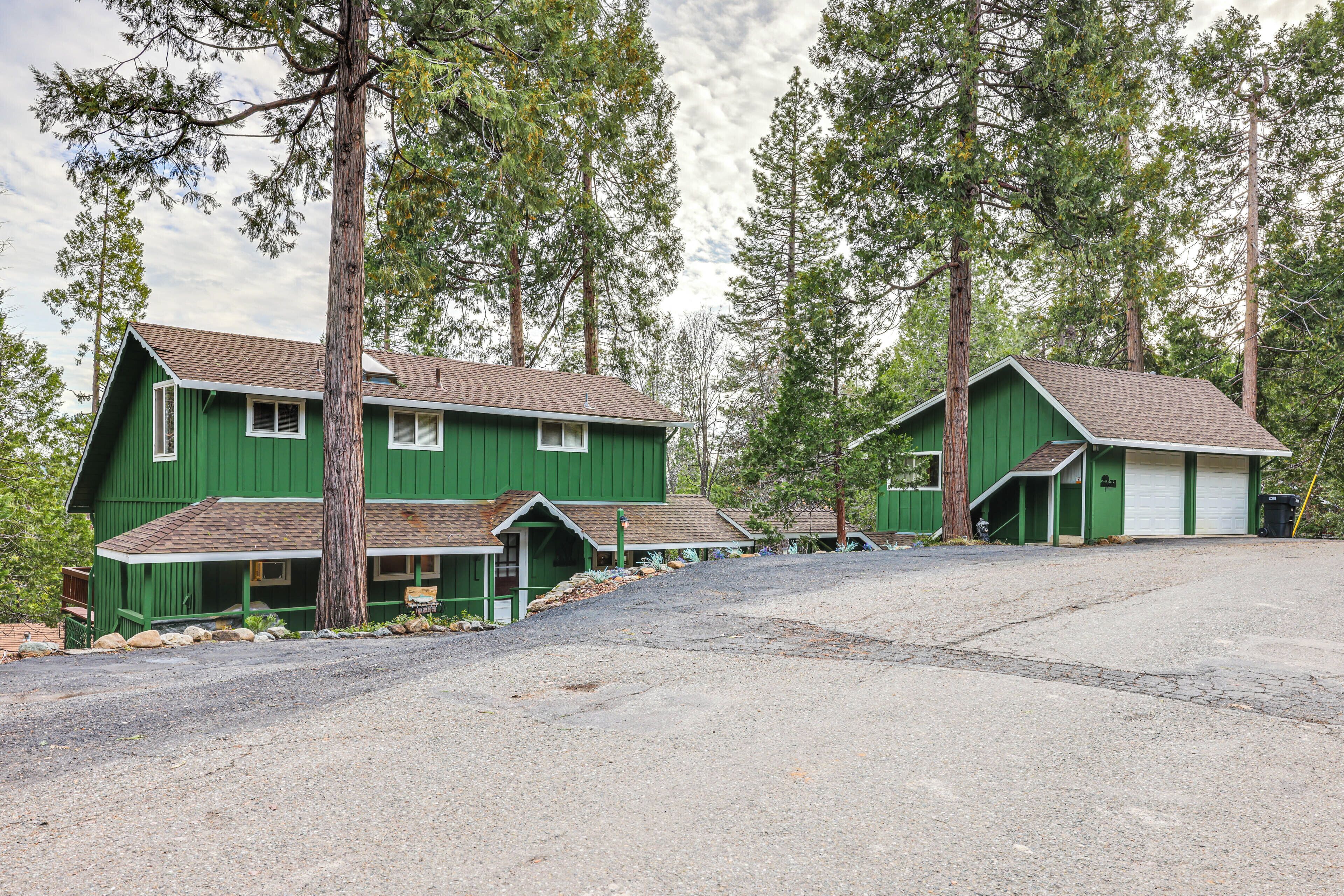 A green two-story house with a front porch, a garage, and a driveway.