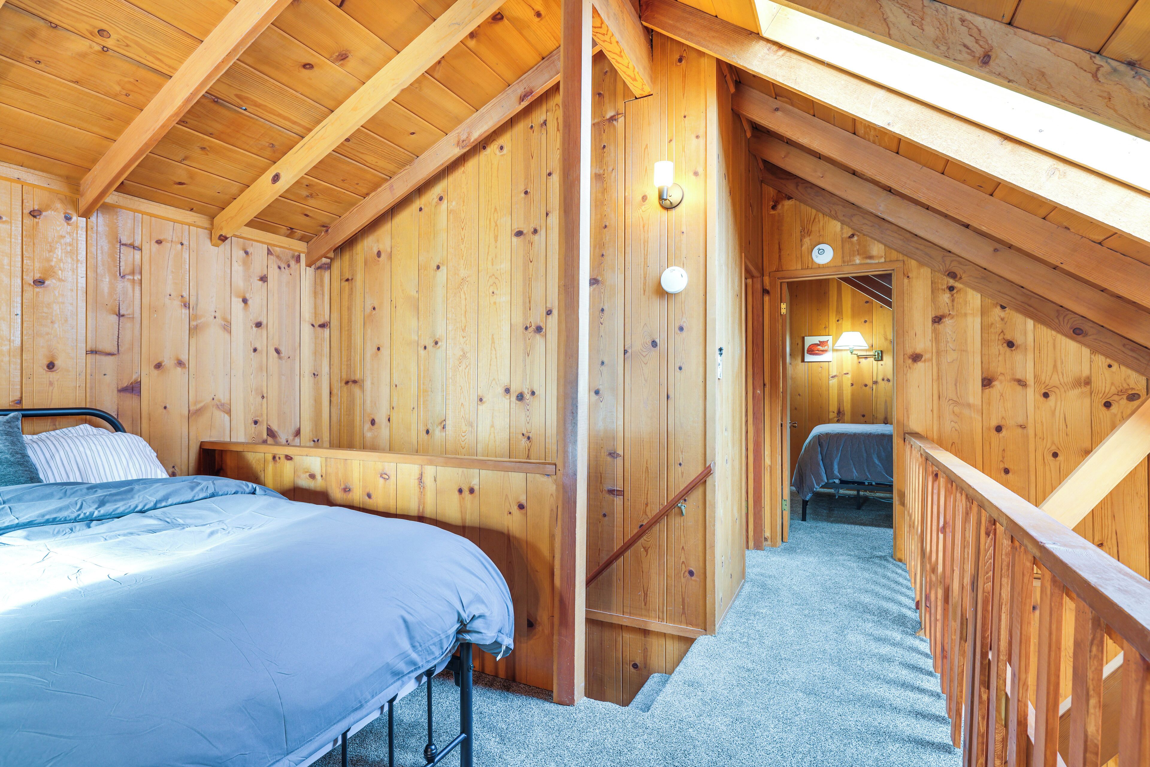 Ein Schlafzimmer in einer Holzhütte mit einem Bett, einem Nachttisch und einer Holztreppe.
