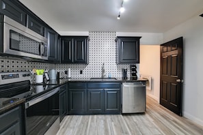 A modern kitchen with dark cabinetry, a stainless steel microwave, and a dishwasher. - 'little Elm Pearl' Near Park & Lewisville Lake! (Little Elm)