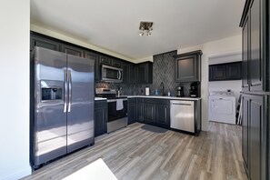 Una cocina moderna con gabinetes oscuros, electrodomésticos de acero inoxidable y suelo de madera.