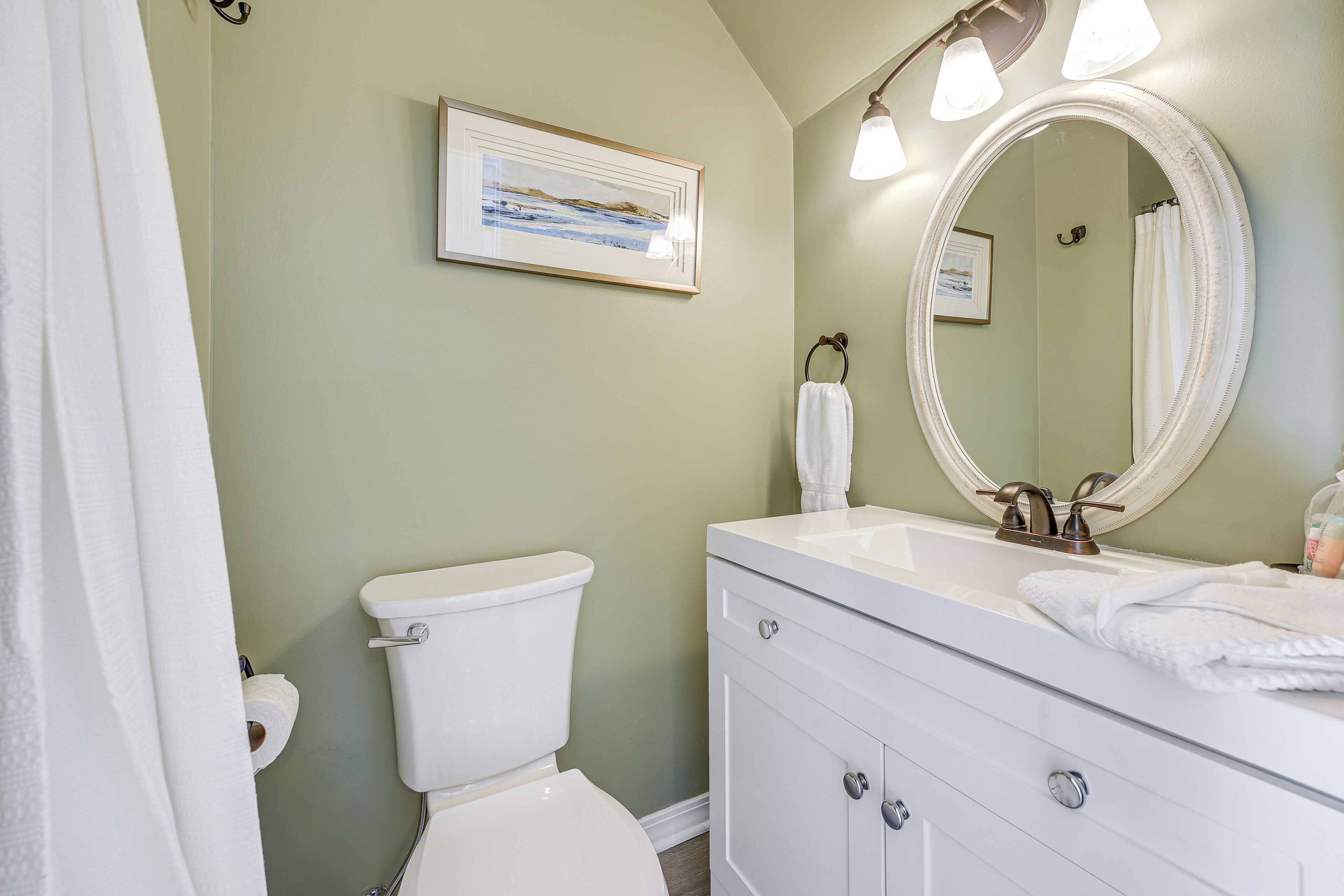 A bathroom with a toilet, sink, and mirror.