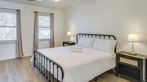 A neatly made bed with white linens, a bedside table with a lamp, and a ceiling fan. - 1 Mi to Beach: Cozy Grand Strand Townhome! (North Myrtle Beach)