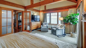 A spacious bedroom with a large bed, a television, two armchairs, a potted plant, and a view of the outdoors. - Luxury Vashon Vacation Rental w/ Beach Access! (Vashon Island)