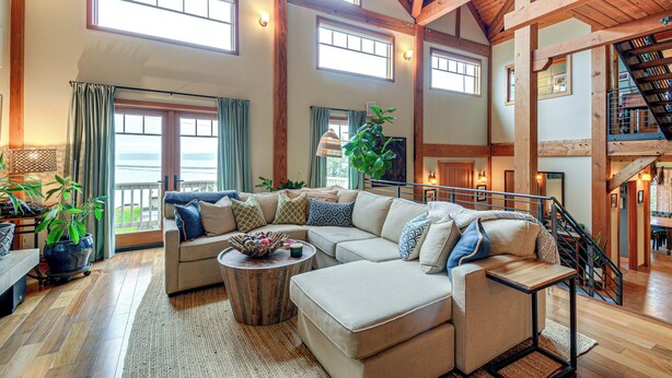 A spacious living room with a large sectional sofa, a coffee table, and a staircase leading to an upper level. - Luxury Vashon Vacation Rental w/ Beach Access! (Vashon Island)