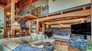A spacious living area with a large sofa, a television, and a staircase leading to an upper level. - Luxury Vashon Vacation Rental w/ Beach Access! (Vashon Island)