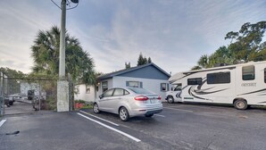 Een parkeerplaats met een zilvergrijze auto en een grote camper.