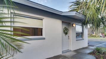 A single-story building with a white exterior, a front door with a wreath, and a window with a view of the street.