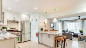 Una cocina moderna con electrodomésticos de acero inoxidable, una isla central con taburetes y una zona de comedor con mesa y sillas.
