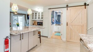 Una cocina moderna con encimera de mármol, armarios blancos y una puerta de estilo rústico.