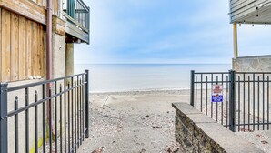 Una propiedad frente a la playa con entrada protegida, un edificio de madera a la izquierda y un muro de piedra a la derecha.