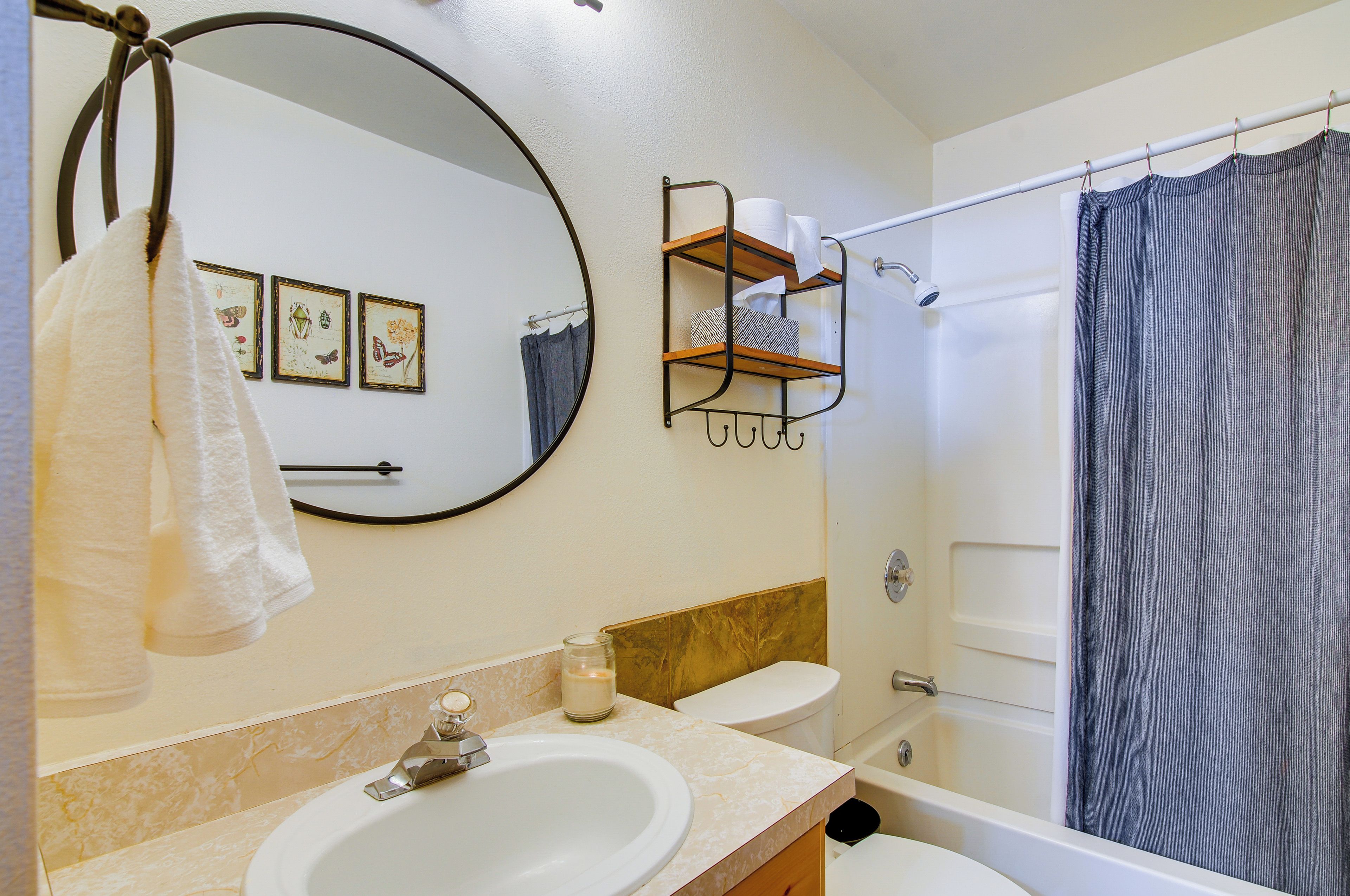 Une salle de bain équipée d’un lavabo, d’un miroir, d’un porte-serviettes, de toilettes et d’un rideau de douche.