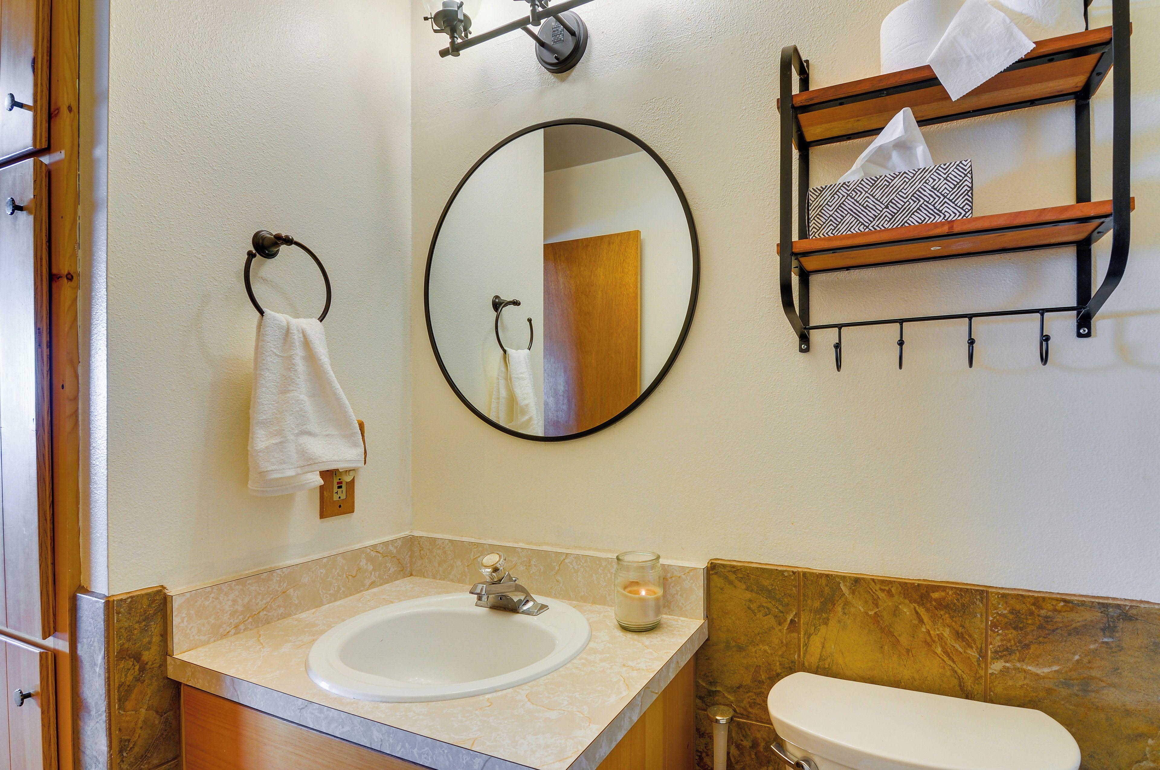 A bathroom with a sink, mirror, towel rack, and a shelf with towels.