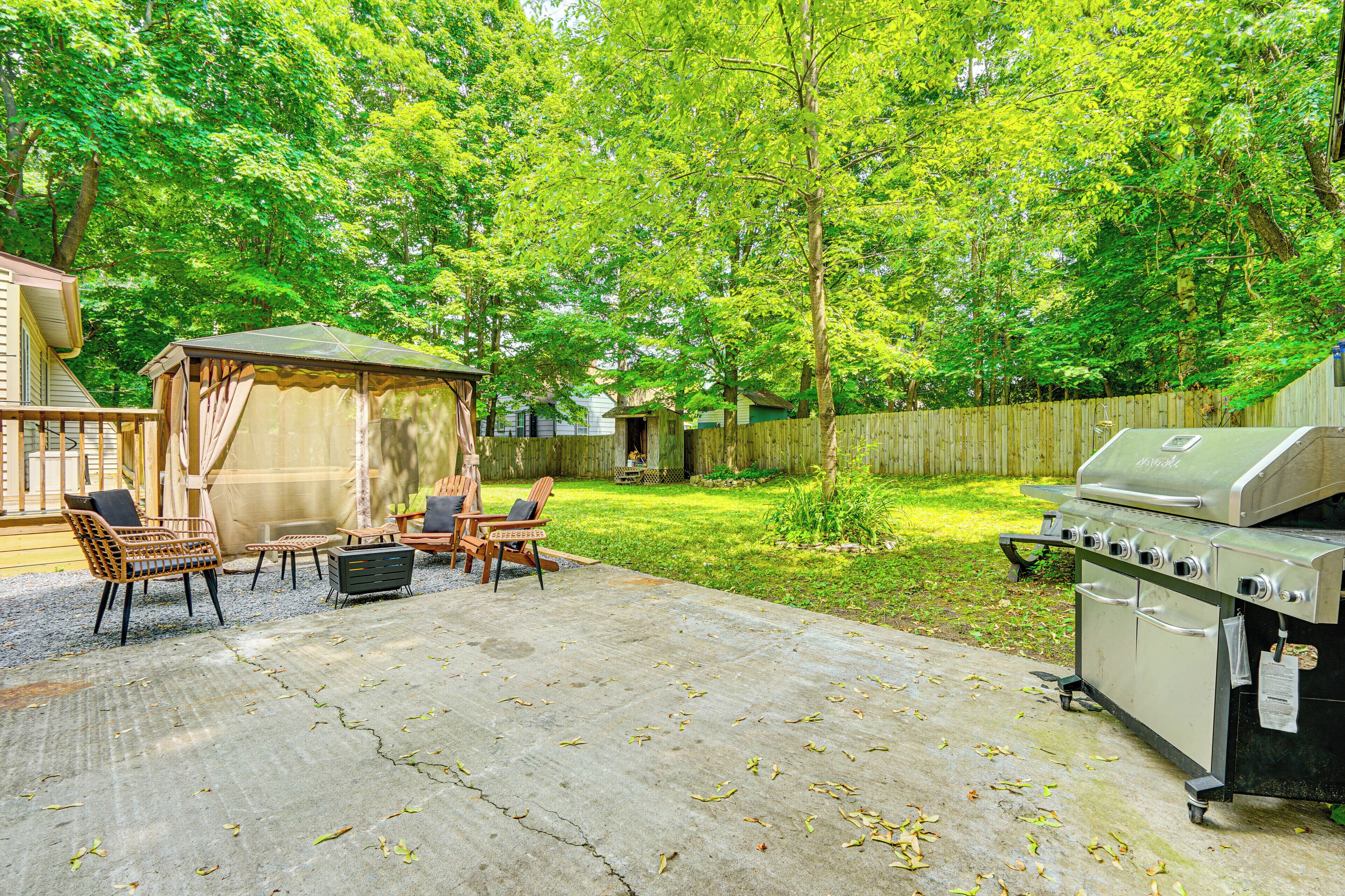 A backyard with a grill, outdoor furniture, and a covered seating area.
