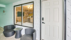 Ein Zimmer mit einer weißen Tür, einem großen Fenster und zwei Korbstühlen.