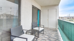 Un balcone con due sedie, un tavolo, una porta e vista sulla città.
