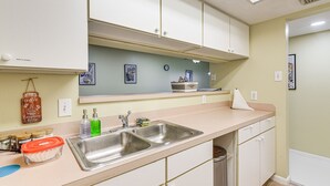 Una cucina con un lavello doppio, mobili bianchi e una parete verde chiaro.