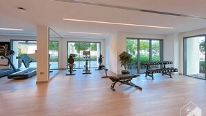 A modern gym with exercise equipment, large windows, and a wooden floor. - Burj Royale Luxury 1bedroom Balcony City View (Dubai)