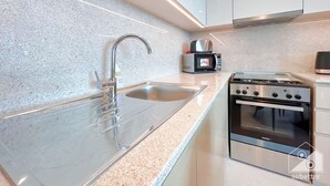 A modern kitchen with a stainless steel sink, a microwave, and a Siemens oven. - Burj Royale Luxury 1bedroom Balcony City View (Dubai)