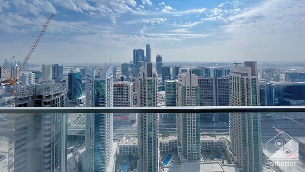A high-rise building with a glass facade, multiple balconies, and a construction crane in the background. - Burj Royale Luxury 1bedroom Balcony City View (Dubai)