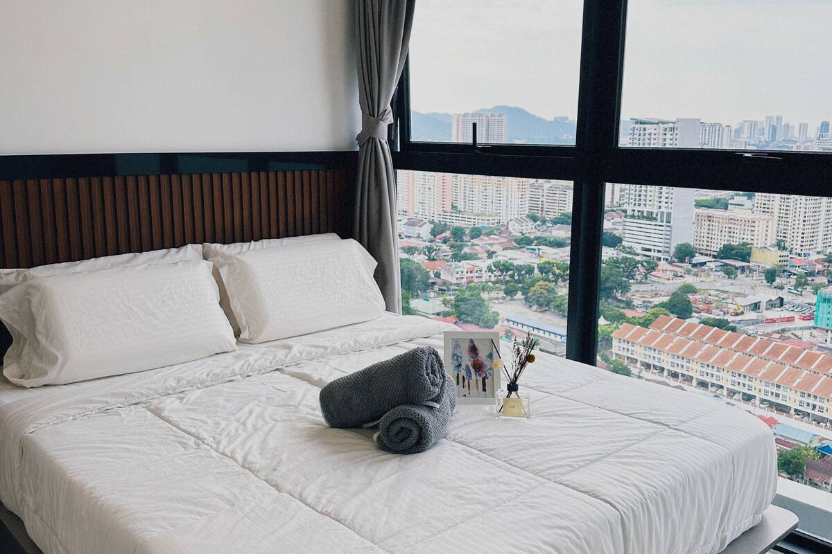 Une chambre d’hôtel avec un grand lit, une vue sur la ville et une fenêtre avec des rideaux.