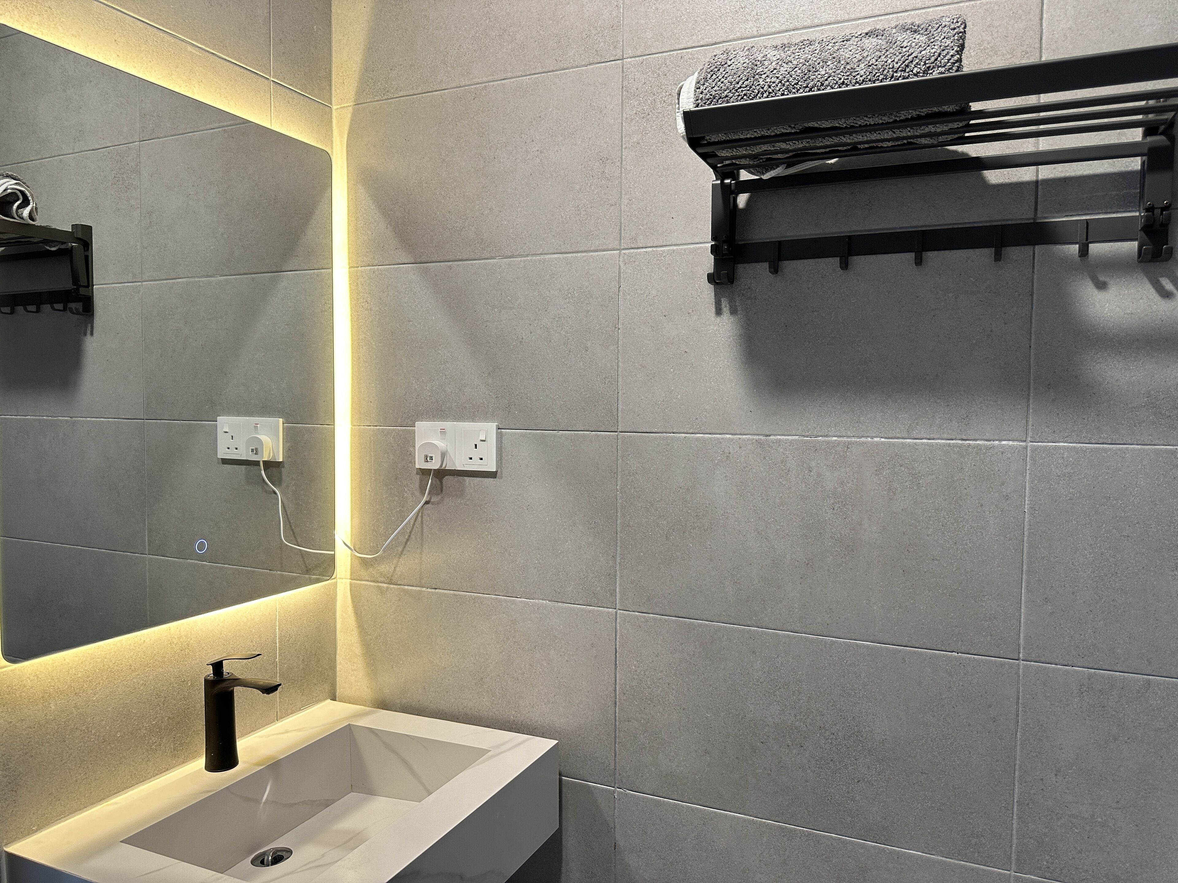 A modern bathroom with a white sink, a mirror, and a towel rack.