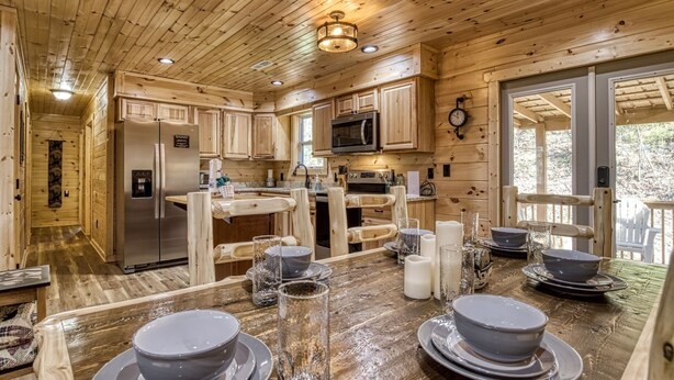 A wooden cabin kitchen with a refrigerator, microwave, stove, and wooden cabinets. - Hilltop Hideaway 3 Bedroom Cabin by RedAwning (Sevierville)