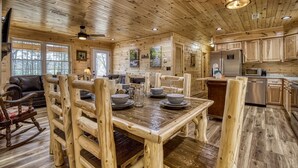 A wooden cabin interior with a dining area, kitchen, and living space. - Hilltop Hideaway 3 Bedroom Cabin by RedAwning (Sevierville)