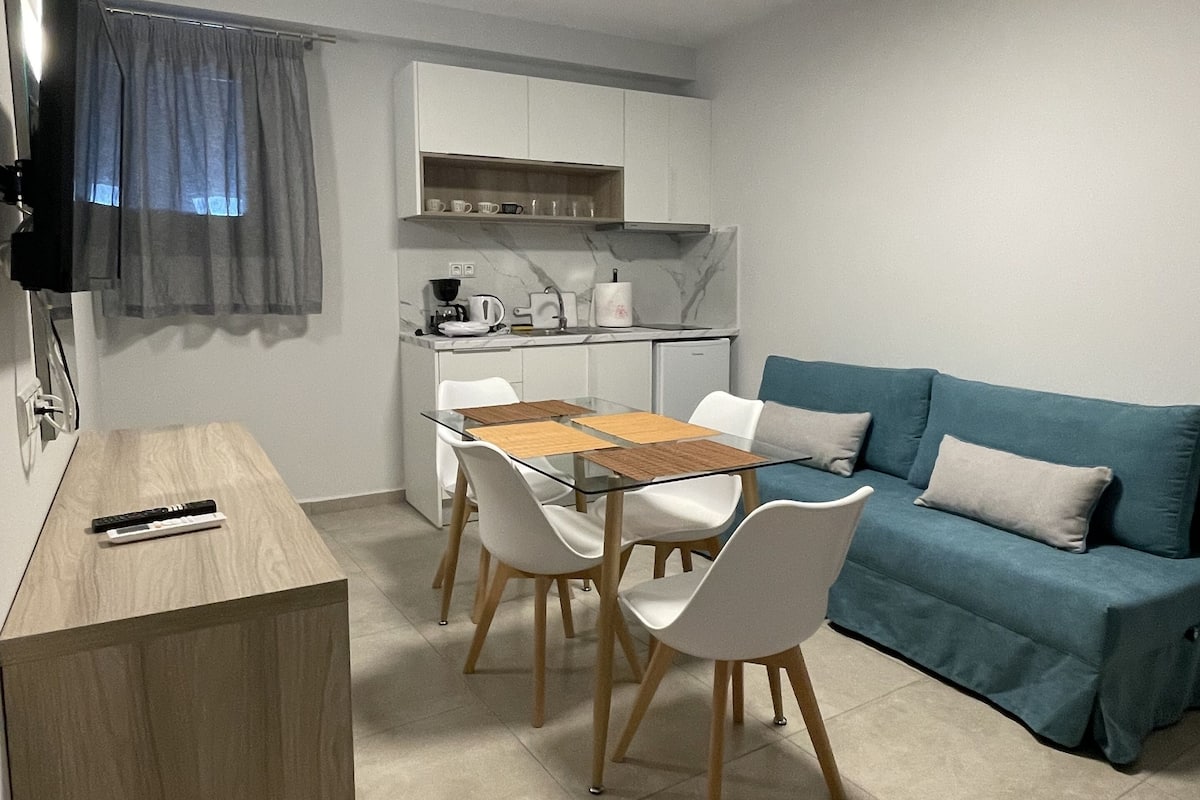 A compact living space with a dining area, a sofa, and a kitchenette.