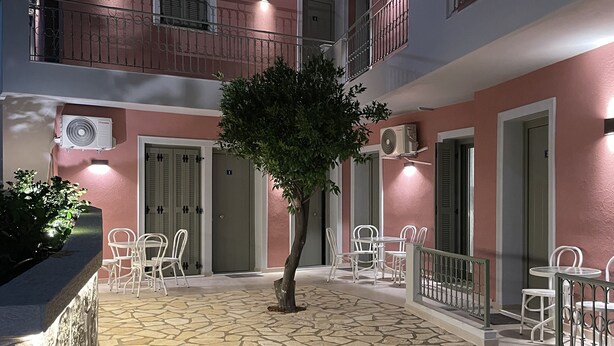A courtyard with a stone floor, a tree, and outdoor seating. - Anax Apartments (Parga)