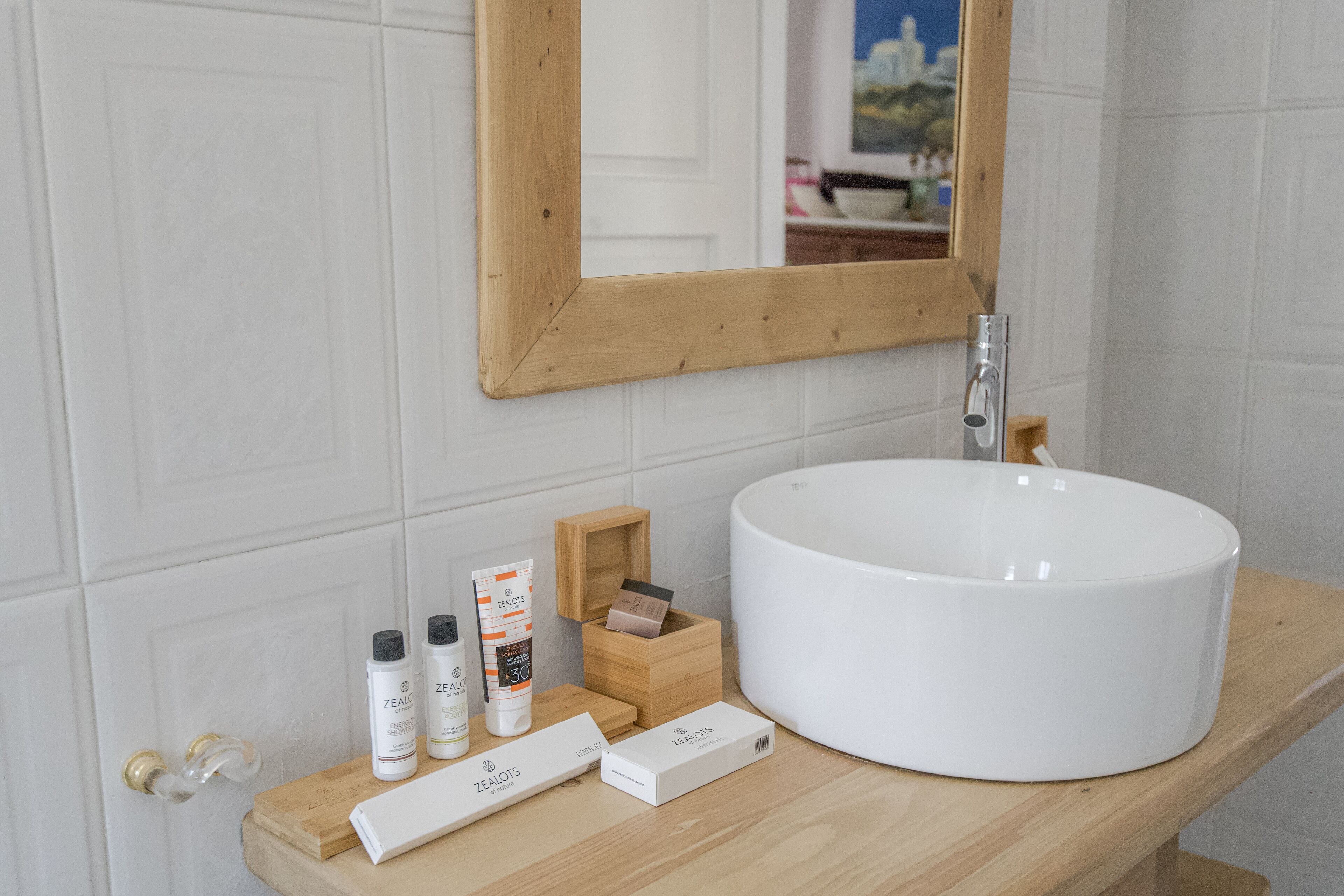 A bathroom with a white sink, wooden vanity, and toiletries.