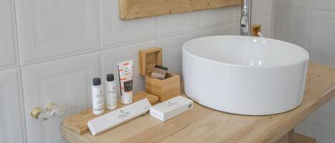 A bathroom with a white sink, wooden vanity, and toiletries.