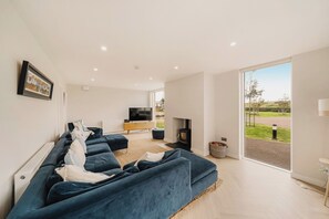 Una sala de estar moderna con un sofá modular, un televisor y una chimenea.
