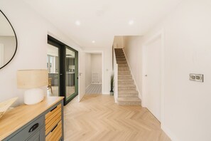 A modern interior with a wooden floor, a staircase, a mirror, and a lamp on a wooden cabinet. - New | Family Haven | Walk to Rossnowlagh Beach | Large Garden | Sauna (Rossnowlagh Lower)