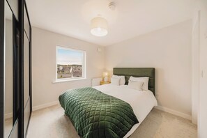 A bedroom with a bed, a window, a bedside lamp, and a view of a residential area. - New | Family Haven | Walk to Rossnowlagh Beach | Large Garden |  Sauna (Rossnowlagh Lower)