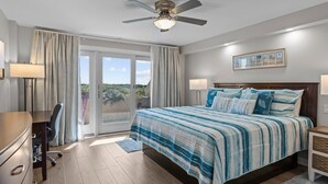 Ein Schlafzimmer mit Bett, Schreibtisch, Stuhl, Deckenventilator und Blick ins Freie.