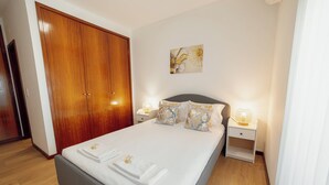 Una cama bien hecha con almohadas y una mesita de noche con una lámpara.