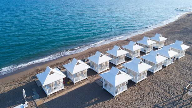 Eine Reihe weißer Strandhütten mit Strand und Meer im Hintergrund.
