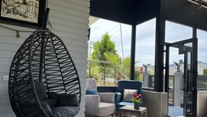 Ein modernes Wohnzimmer mit einem Hängekorbstuhl, einem blauen Sessel und einem kleinen Tisch mit einem Blumentopf.