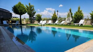 Ein Pool mit klarem, blauem Wasser, umgeben von weißen Liegestühlen und einem gepflegten Rasen.